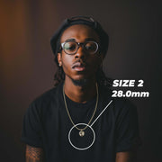 A man wearing round black-rimmed glasses and a black t-shirt, with a gold chain necklace featuring a small circular pendant. White text on the right reads 'SIZE 2'.