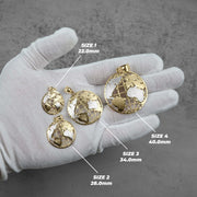 Four gold-toned globe pendant charms displayed on a white gloved hand, with size labels reading SIZE 1 22.0mm, SIZE 2 28.