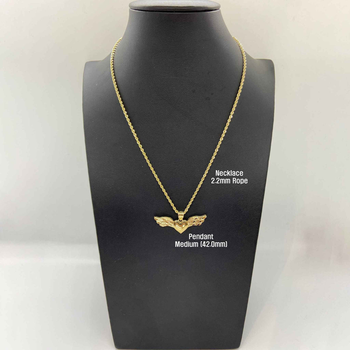 Gold winged heart pendant on a 2.2mm rope chain displayed on a black mannequin.