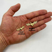 Small and medium gold heart wing pendants resting on an open palm for scale