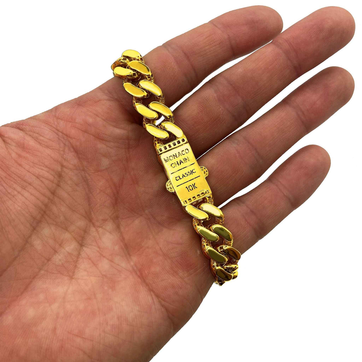 10K yellow gold iced-out Monaco Cuban link chain bracelet held across an open palm.