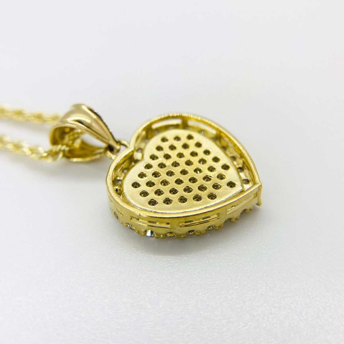 Back view of 10k gold heart pendant showing perforated metal backing and chain loop.