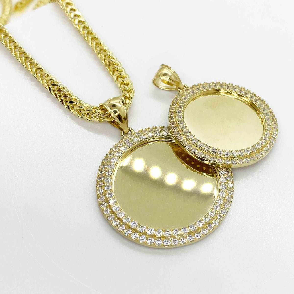 Two 10k gold round photo pendants with cubic zirconia borders shown with chain.