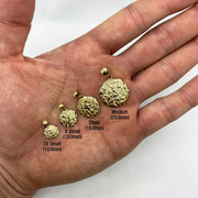 Four gold round nugget pendants in sizes 2X Small to Medium held in hand.
