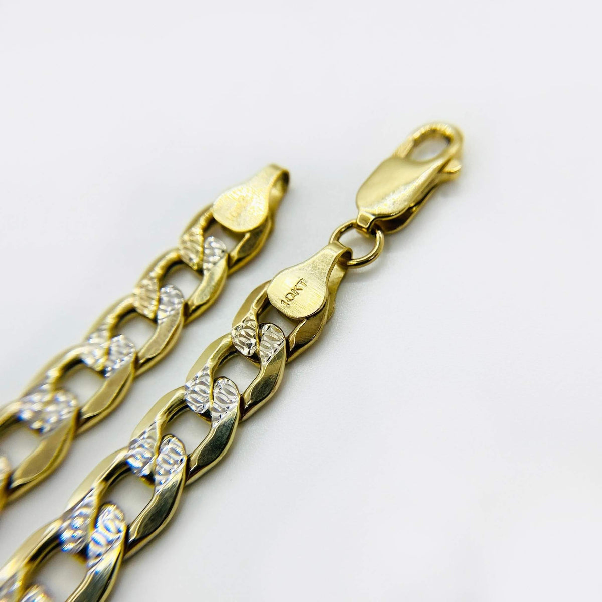 Close-up of a 10k gold pave curb link bracelet showing a lobster clasp and hallmark