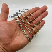 Person holding five 10k gold pave curb link bracelets in varying millimeter widths.