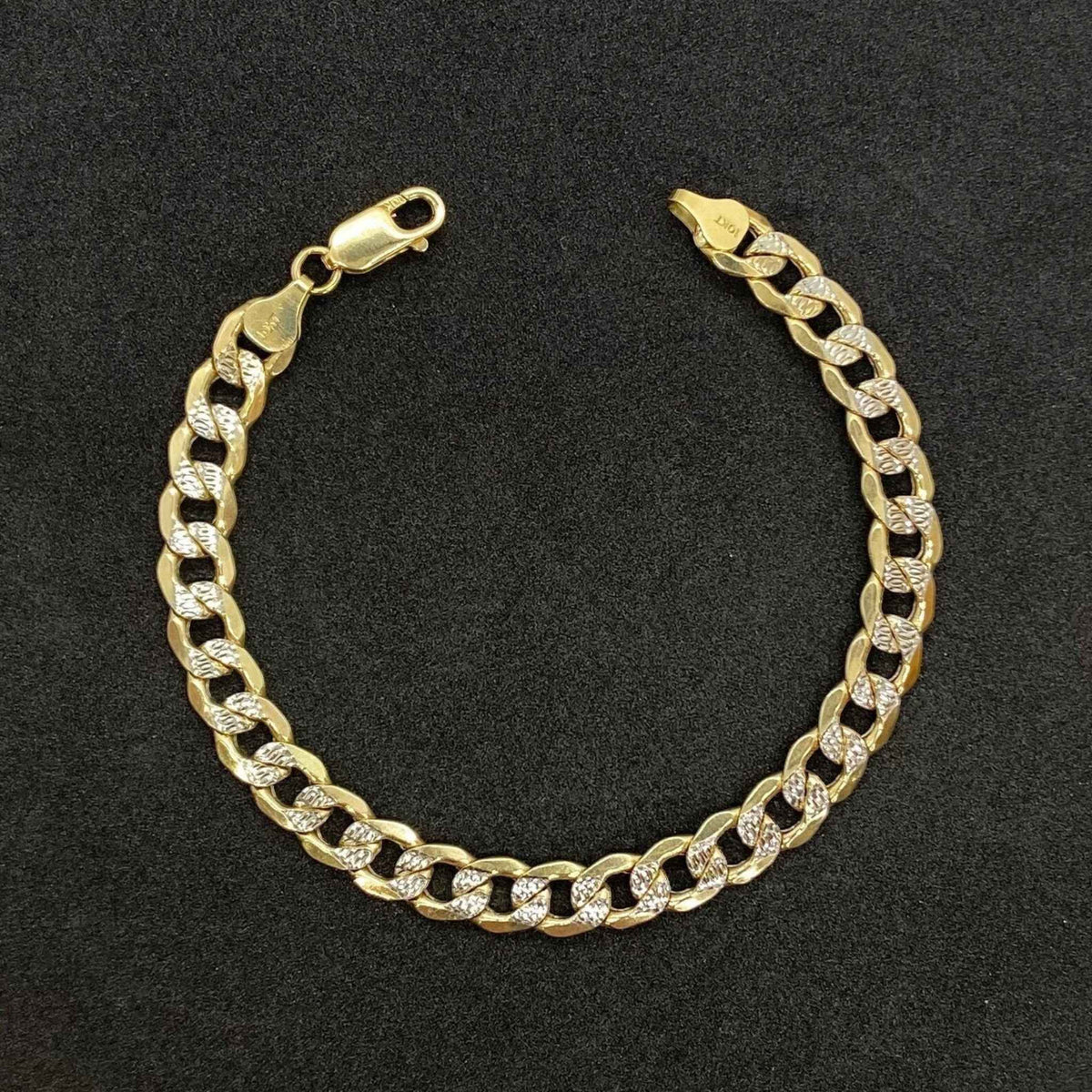 Polished 10k yellow gold Cuban link bracelet featuring diamond-cut pave details.