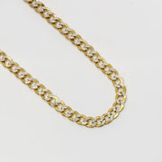 Polished 10k gold pave diamond cut Cuban curb link chain necklace on white background.