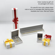 Gold jewelry displayed inside white gift boxes topped with red and yellow ribbons.