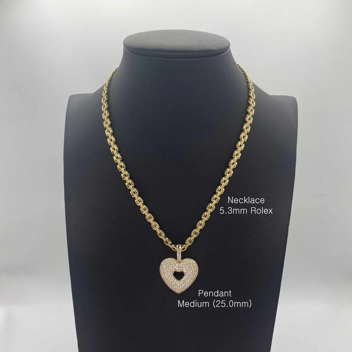 Medium gold CZ heart pendant on a 5.3mm Rolex chain on a bust display.