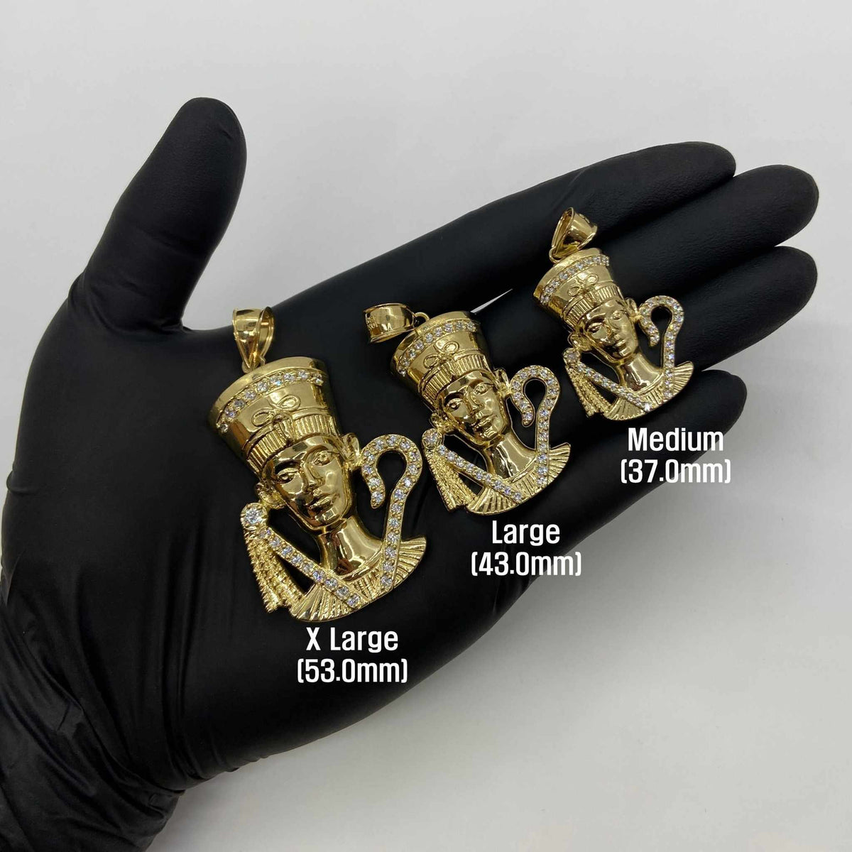 Size comparison of 10k yellow gold Queen Nefertiti CZ pendants displayed on a gloved hand.