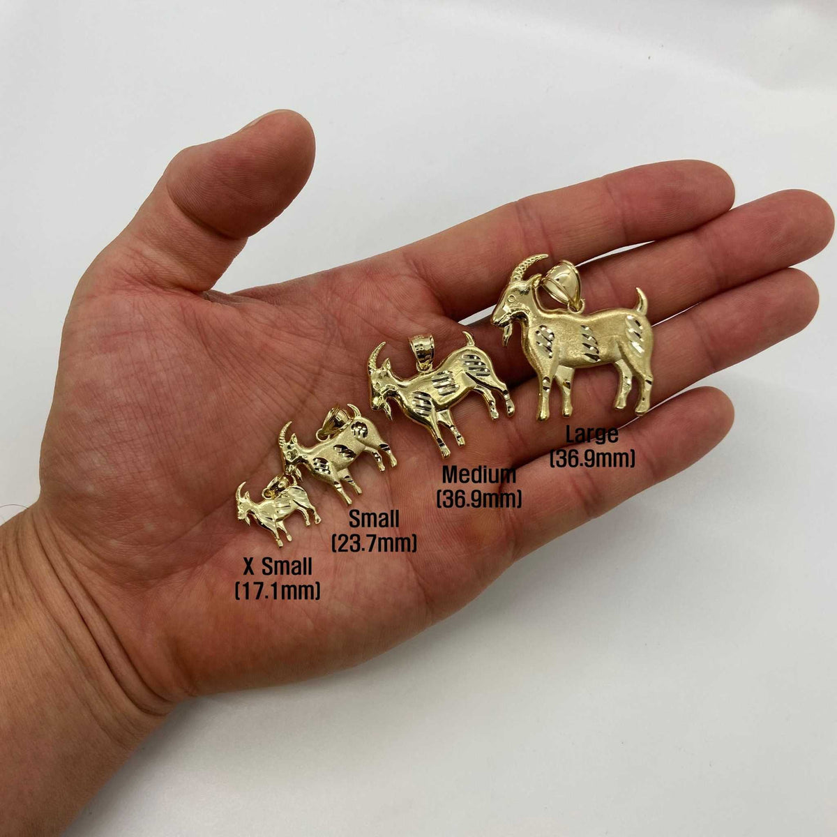 Five sizes of 10k yellow gold satin goat pendants resting on an open palm.
