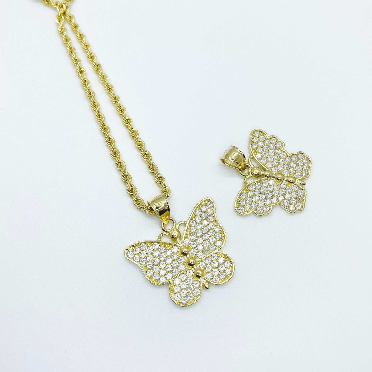 10k yellow gold butterfly CZ pendant on a rope chain next to a separate pendant.