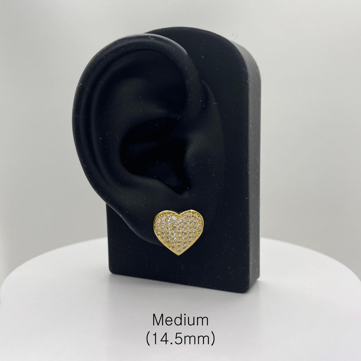 Medium 14.5mm gold heart CZ stud earring on a black ear-shaped jewelry stand.