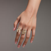 Hand wearing two 10k yellow gold medium vintage cursive initial rings on gray background.