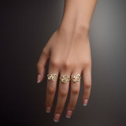 Hand wearing three 10k yellow gold vintage nugget initial rings on a dark background.