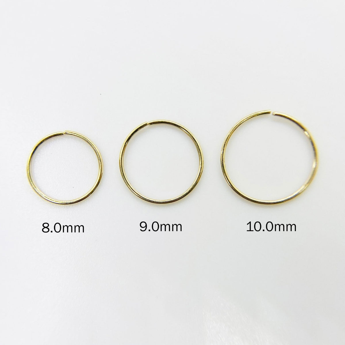 Three 14k gold nose hoops in 8.0mm, 9.0mm, and 10.0mm size comparison.