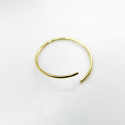 A thin, open-ended 14k gold nose hoop isolated on a white background.