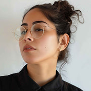 A woman wearing a two-tone 14k gold San Judas stud earring in her earlobe.