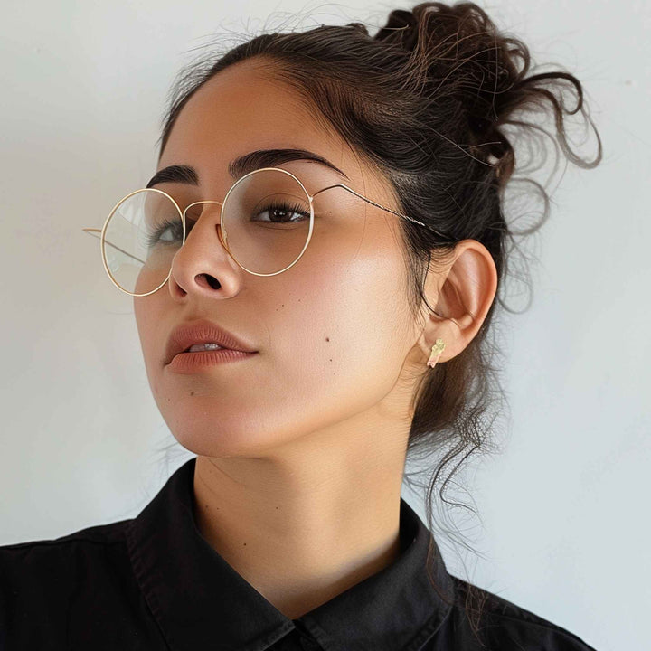 A woman wearing a two-tone 14k gold San Judas stud earring in her earlobe.
