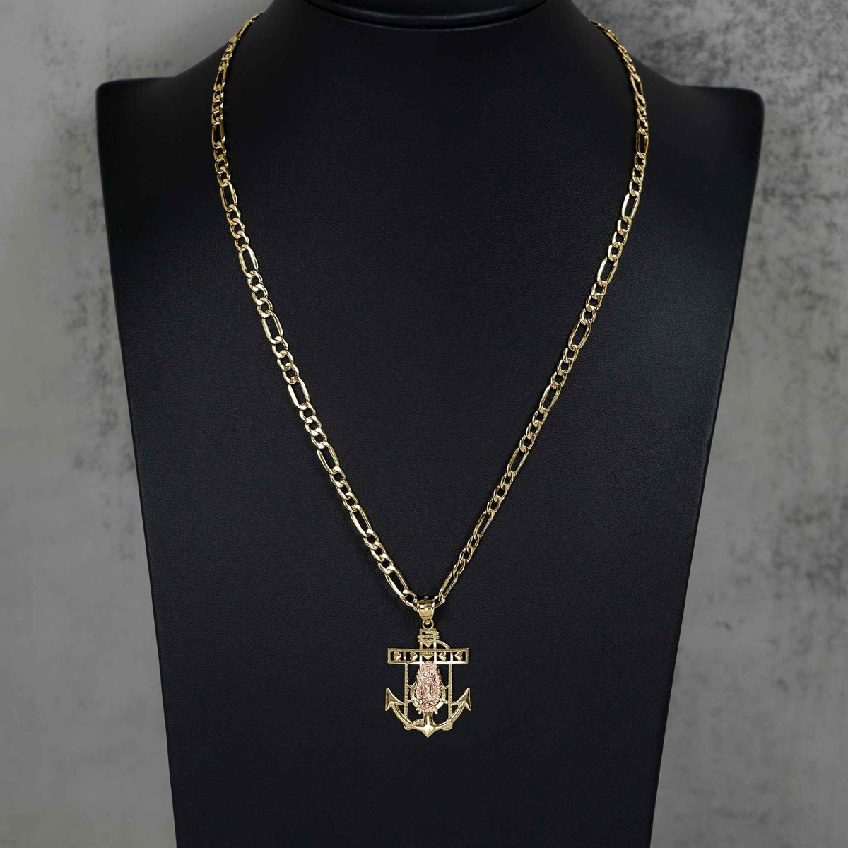 Close-up of the 14k gold two-tone anchor pendant worn on a Figaro chain.