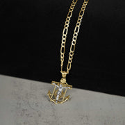 Angled view of a 14k two-tone gold crucifix anchor pendant necklace on a two-tone surface.