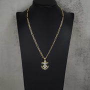 A gold chain necklace with a crucifix anchor pendant displayed on a black mannequin bust