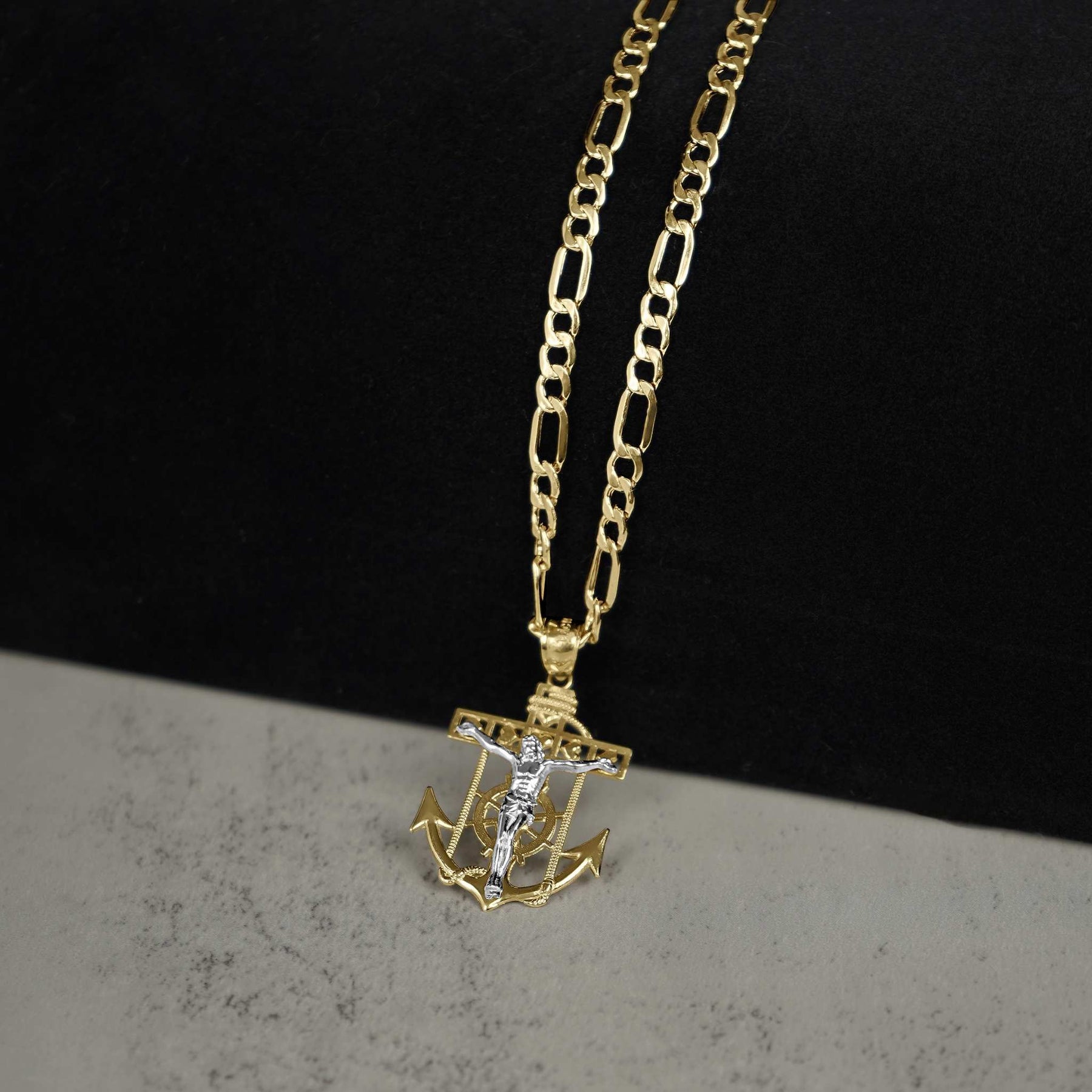 14k gold crucifix anchor pendant necklace displayed on a split black and gray background.