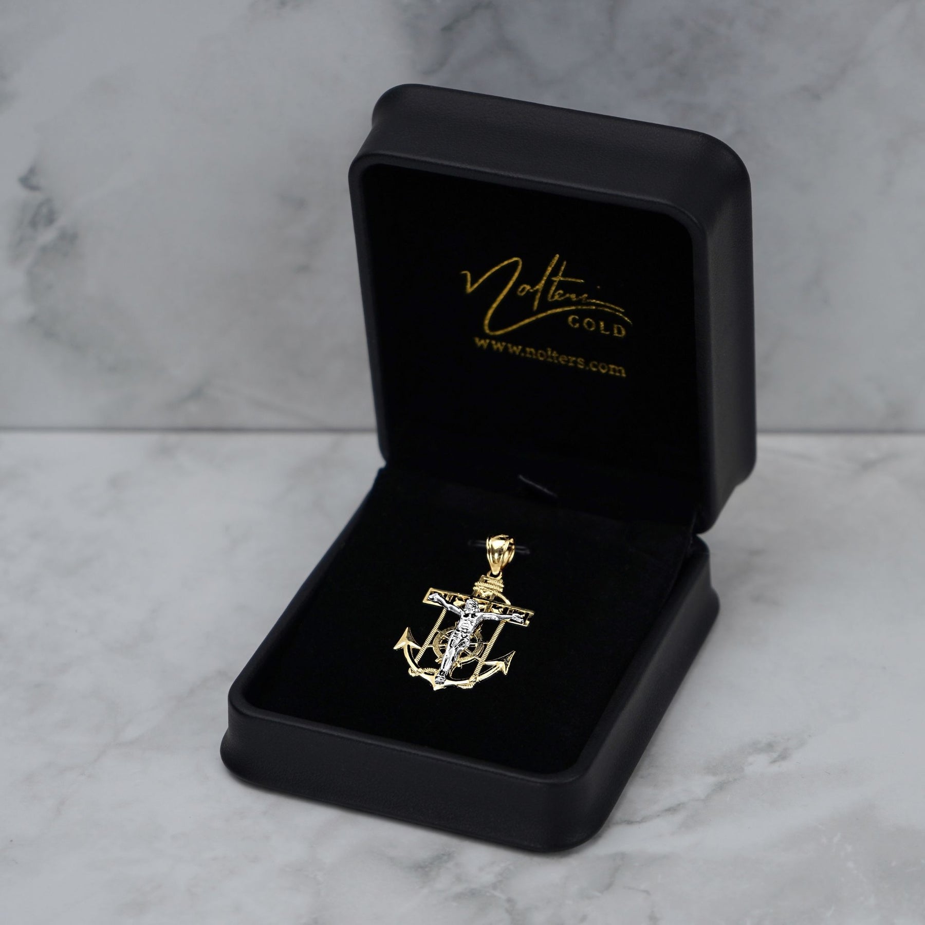 14k gold anchor pendant displayed inside an open black velvet gift box on marble.
