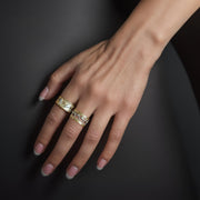 A woman’s hand wearing a two-tone 14k gold dolphin wide band ring.