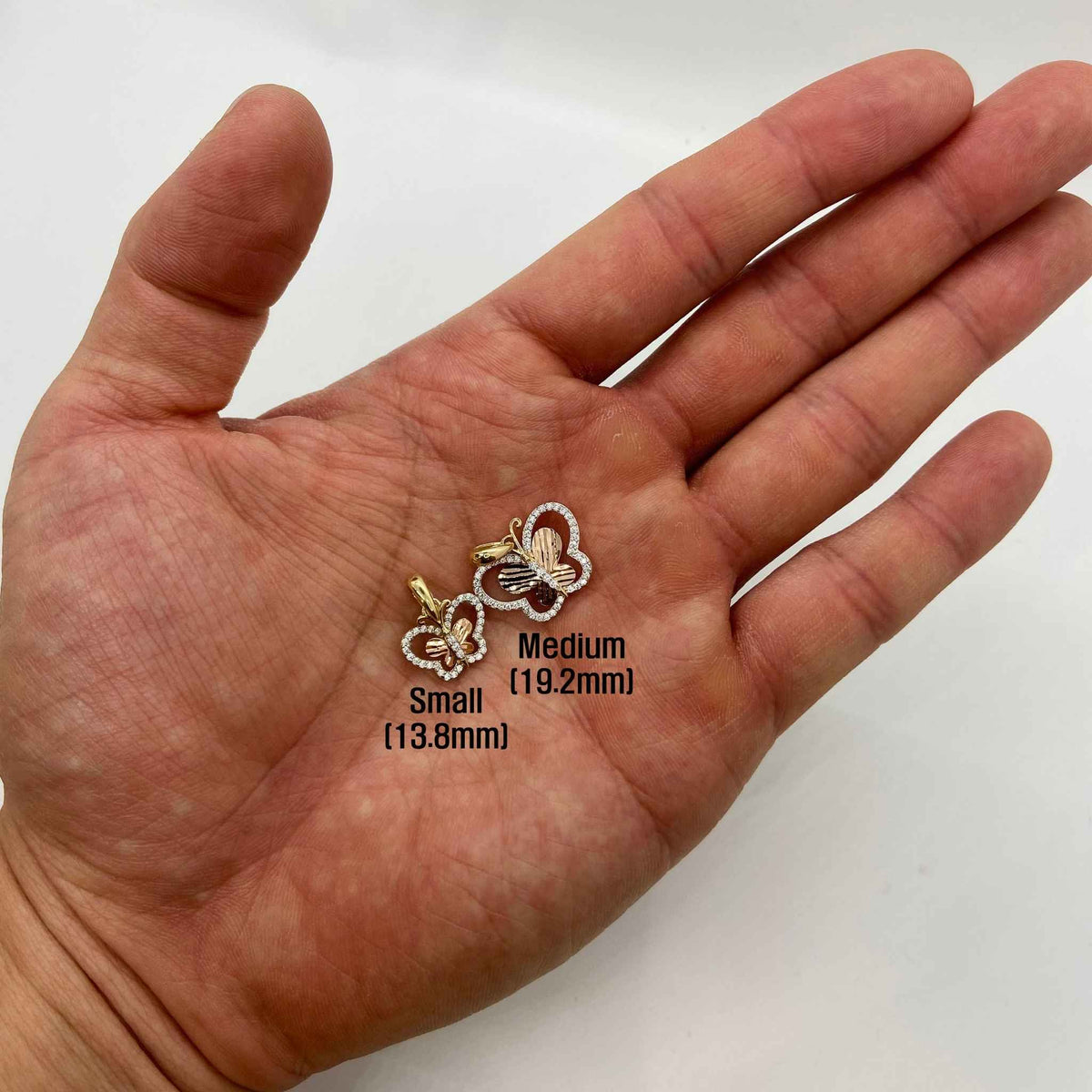 Hand-held size comparison of Small and Medium 14k gold tri-color butterfly charm pendants.