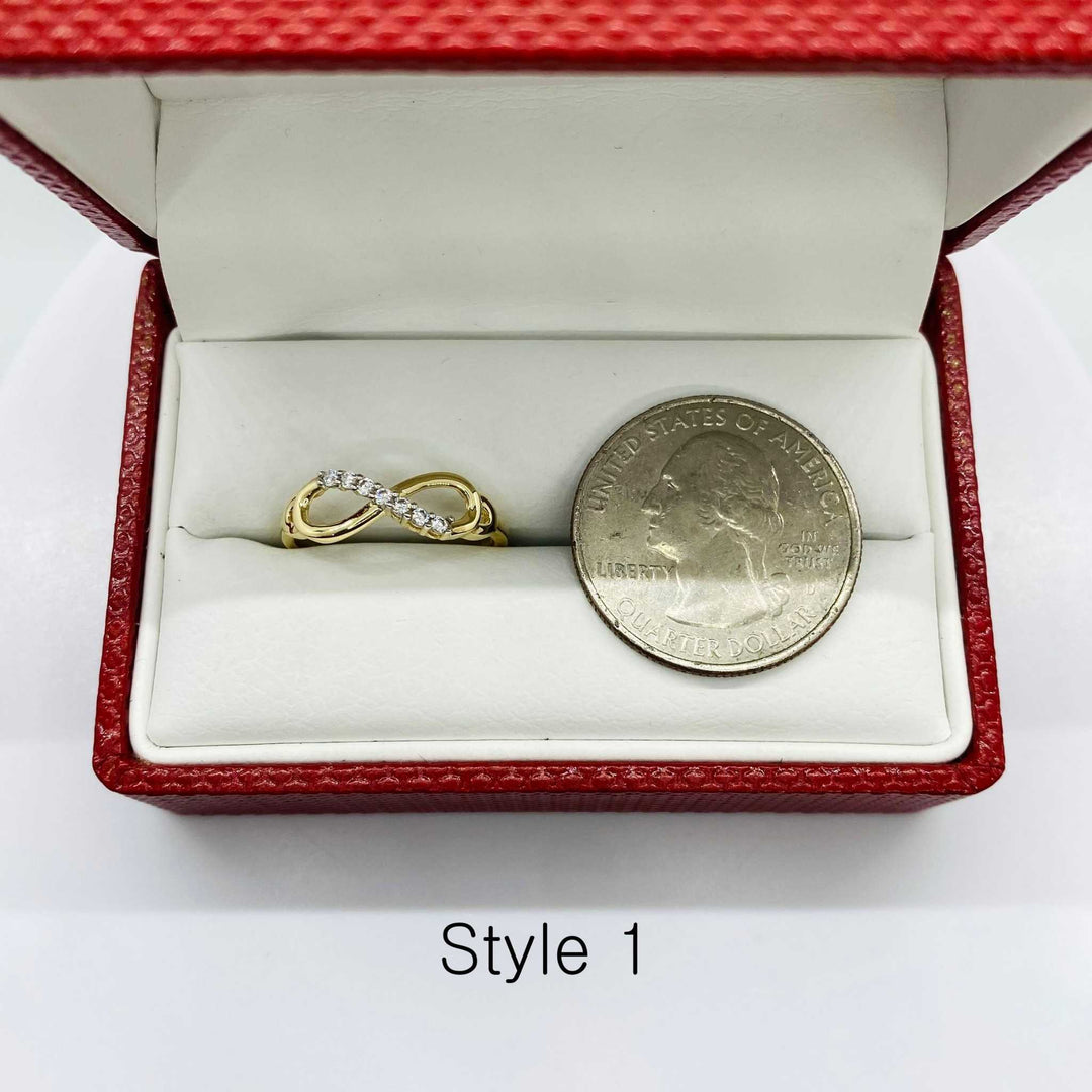 14k Gold ring with infinity design and silver coin next to it for reference in a red jewelry box