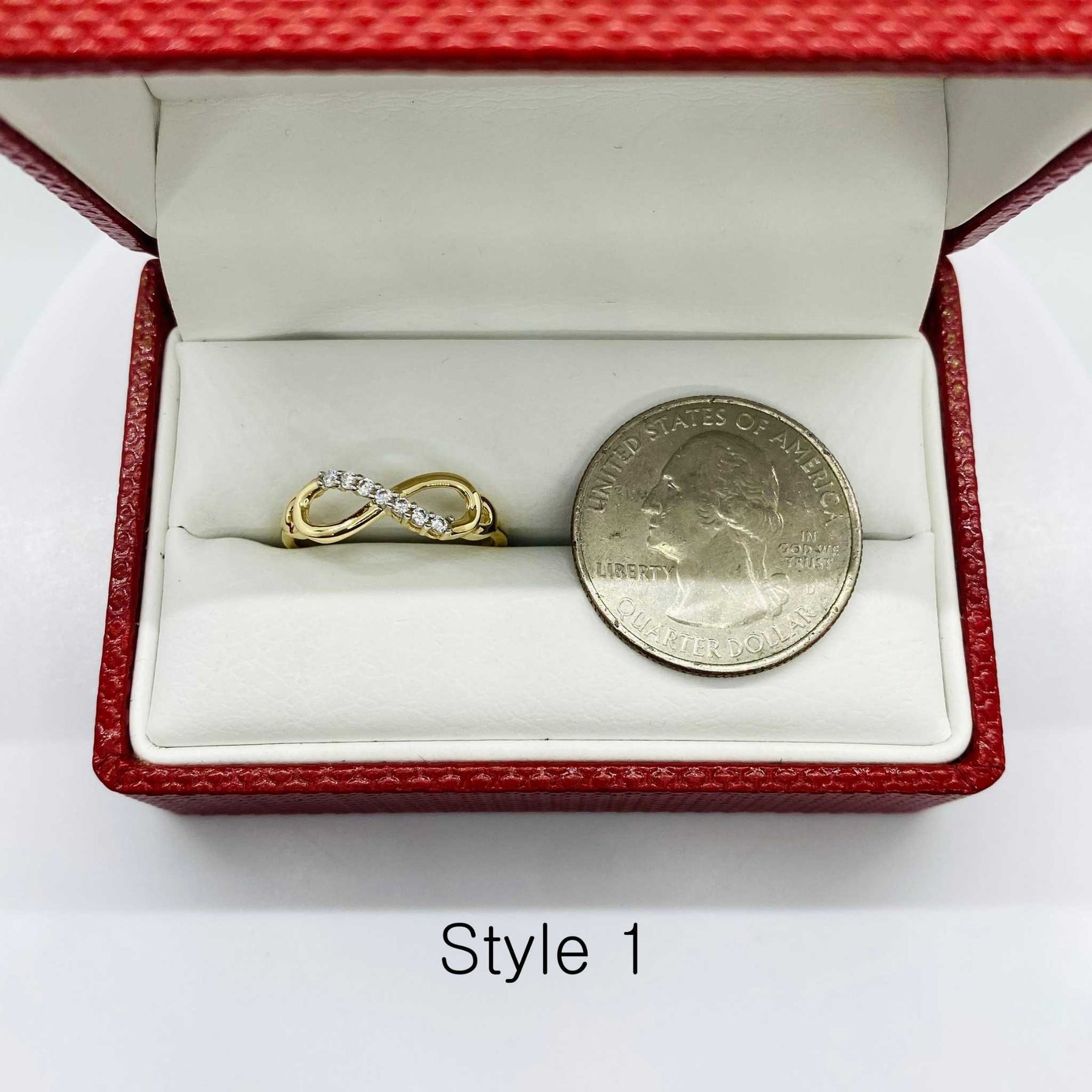 14k Gold ring with infinity design and silver coin next to it for reference in a red jewelry box