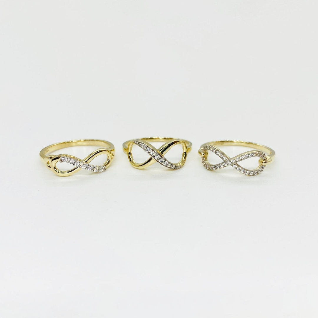 Three 14k gold infinity rings with Cubic Zirconia accents on a light gray background