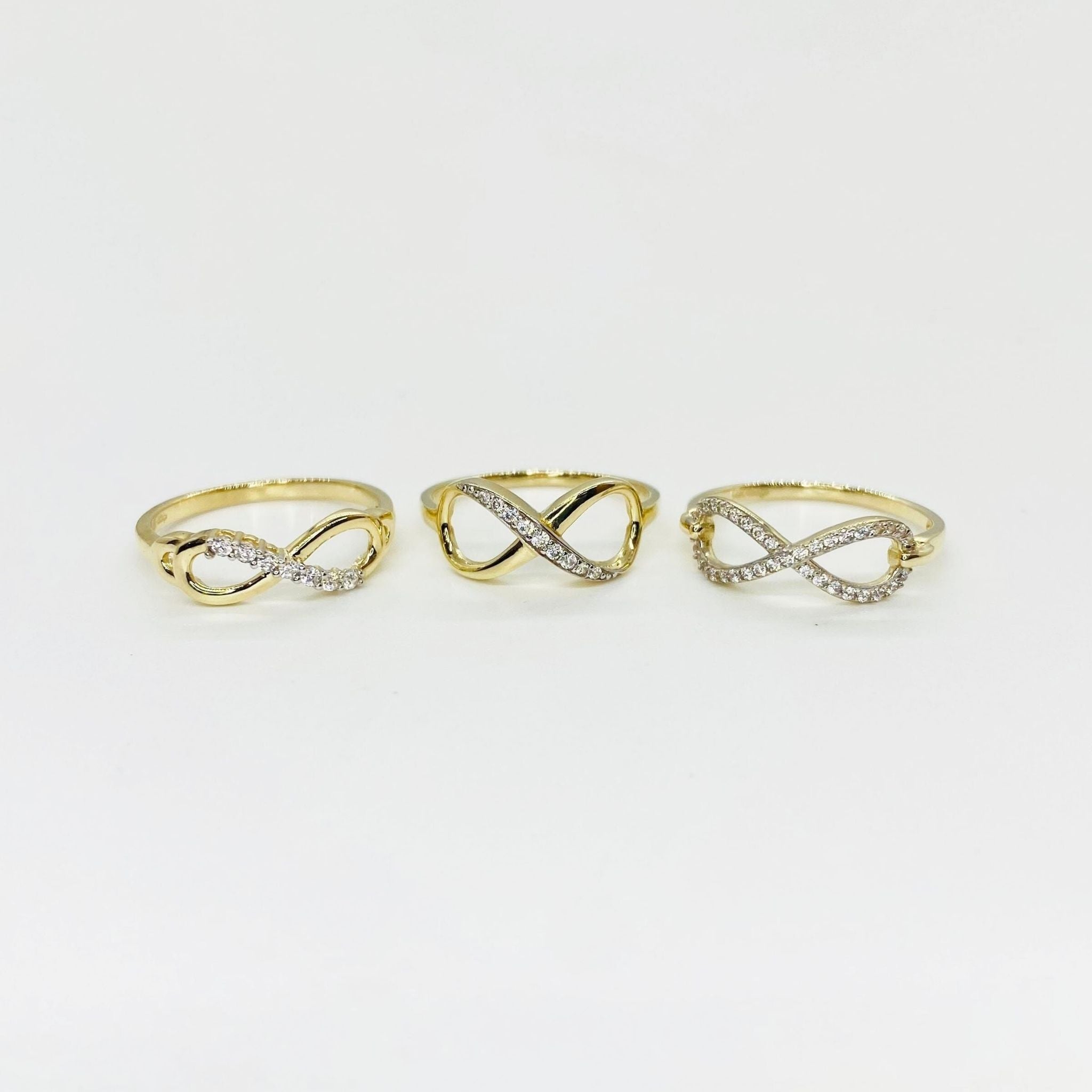 Three 14k gold infinity rings with Cubic Zirconia accents on a light gray background