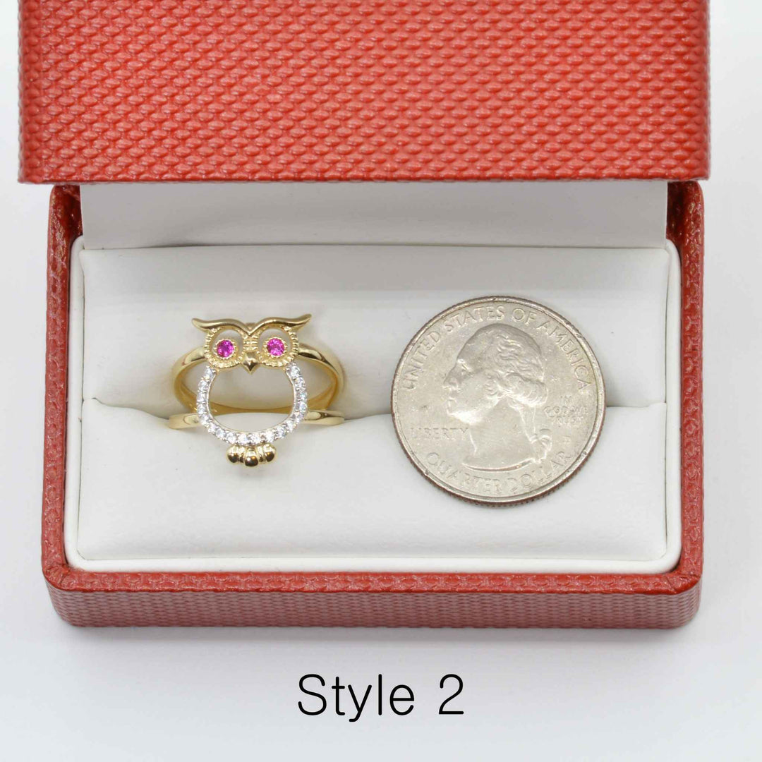14k Gold owl ring with pink and white  Cubic Zirconia in a red jewelry box next to a silver coin.