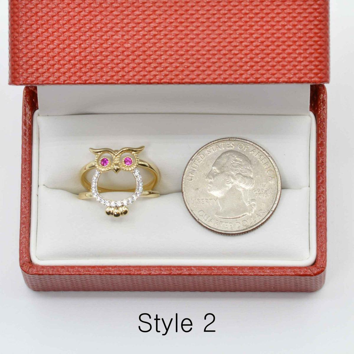 14k Gold owl ring with pink and white  Cubic Zirconia in a red jewelry box next to a silver coin.
