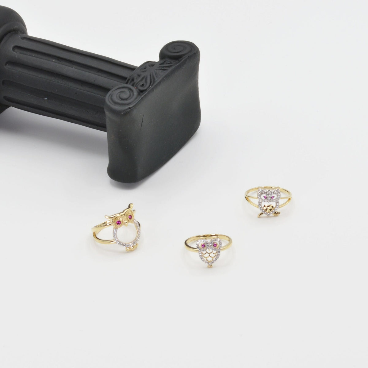 14k Gold owl rings with Cubic Zirconiaon a white surface with a black handle in the background