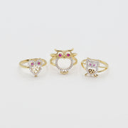 Three 14k gold owl shaped rings with different styles on a white background
