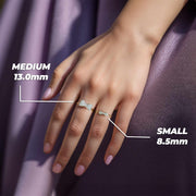 A woman’s hand wearing two gold bow rings with labeled millimeter size comparisons.