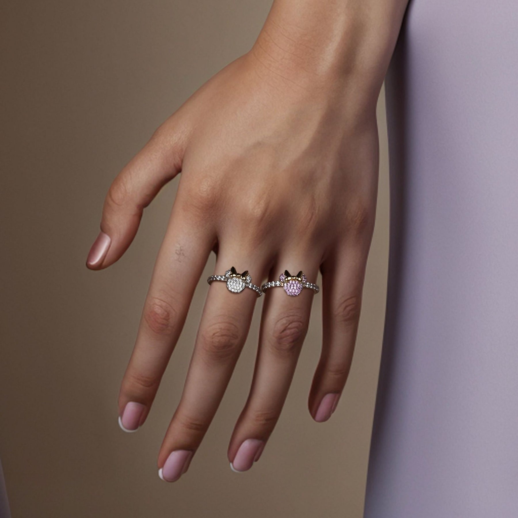 Two sparkling, stone-encrusted gold mouse rings beautifully styled and worn together on a hand.