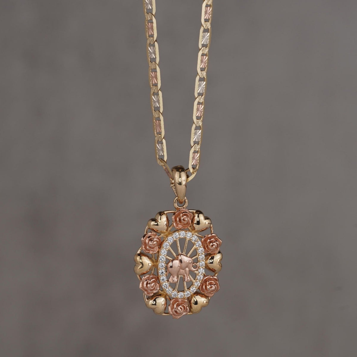 14k tricolor gold oval pendant featuring a rose gold elephant framed by CZ stones and roses.