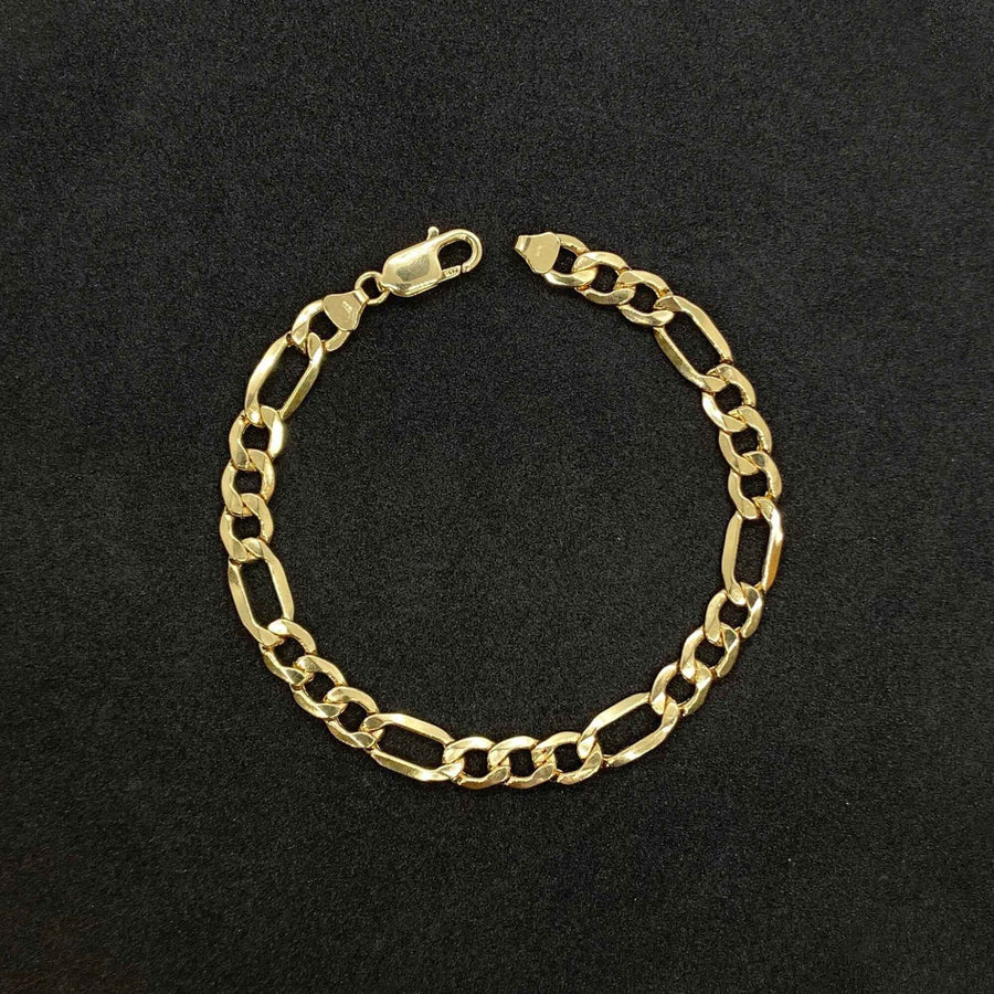 14k yellow gold classic Figaro link chain bracelet displayed on a textured black background.
