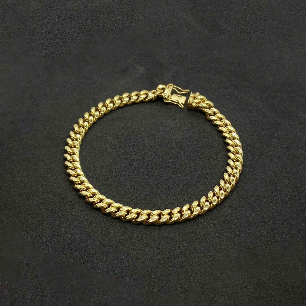 Circular 14k yellow gold Cuban chain bracelet featuring open box lock clasp layout.