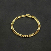 Polished 14k yellow gold classic Miami Cuban chain bracelet on dark background.
