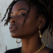 Gold nugget nose piercing stud modeled on a woman with dreadlocks.