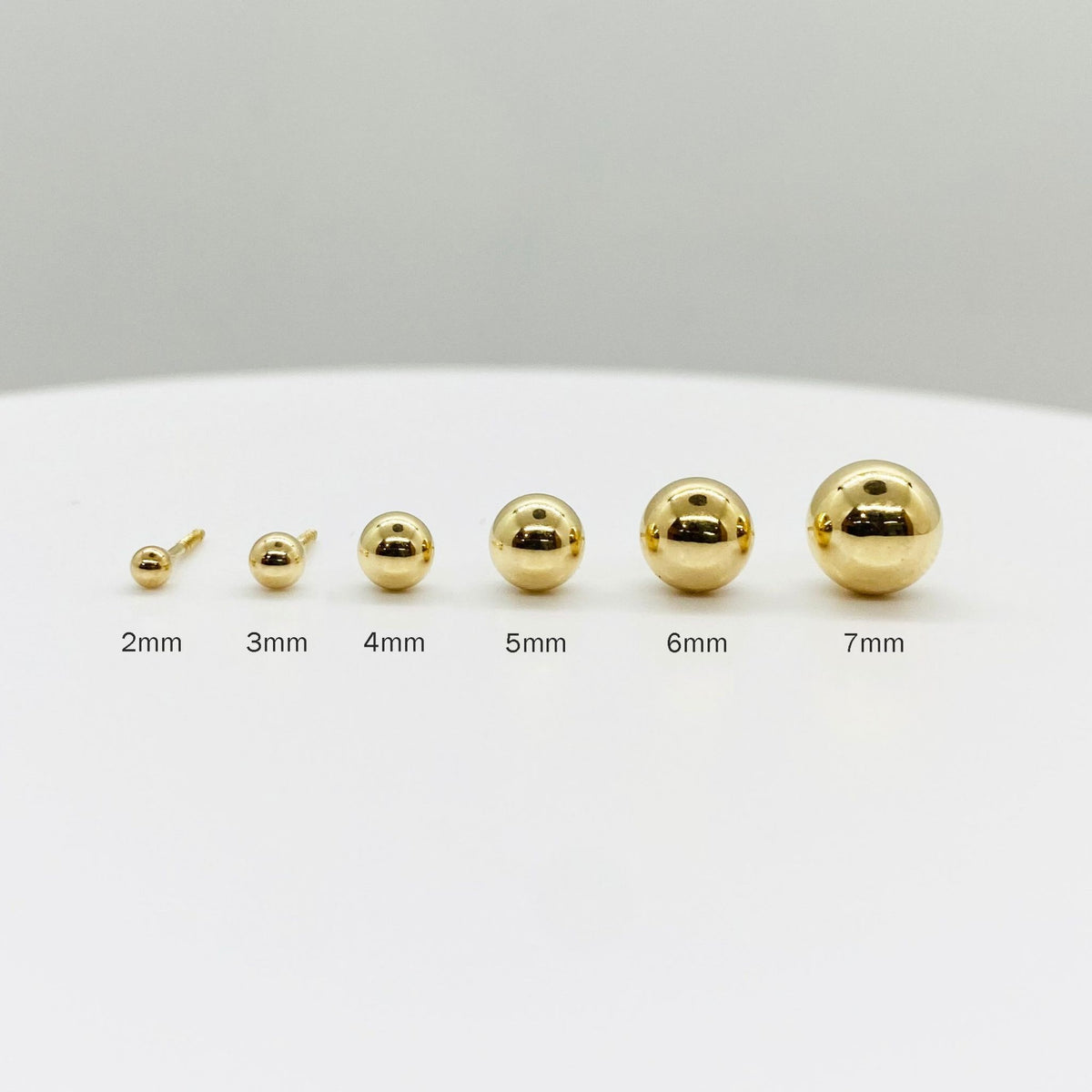Size guide for 14k yellow gold ball stud earrings, showing 2mm to 7mm options for scale.