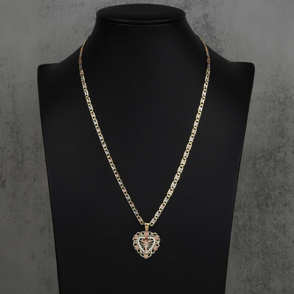 14k gold crucifix bloom rose heart pendant styled on a tricolor chain over a black mannequin bust.