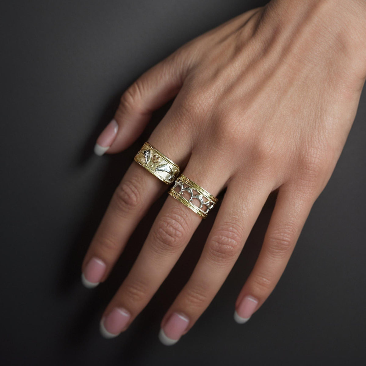 Lifestyle view of 14k gold dolphin tri-color wide band ring styled with another ring.