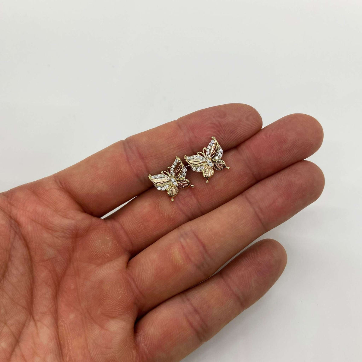 14k gold Elan butterfly stud earrings hand size perspective jewelry scale.